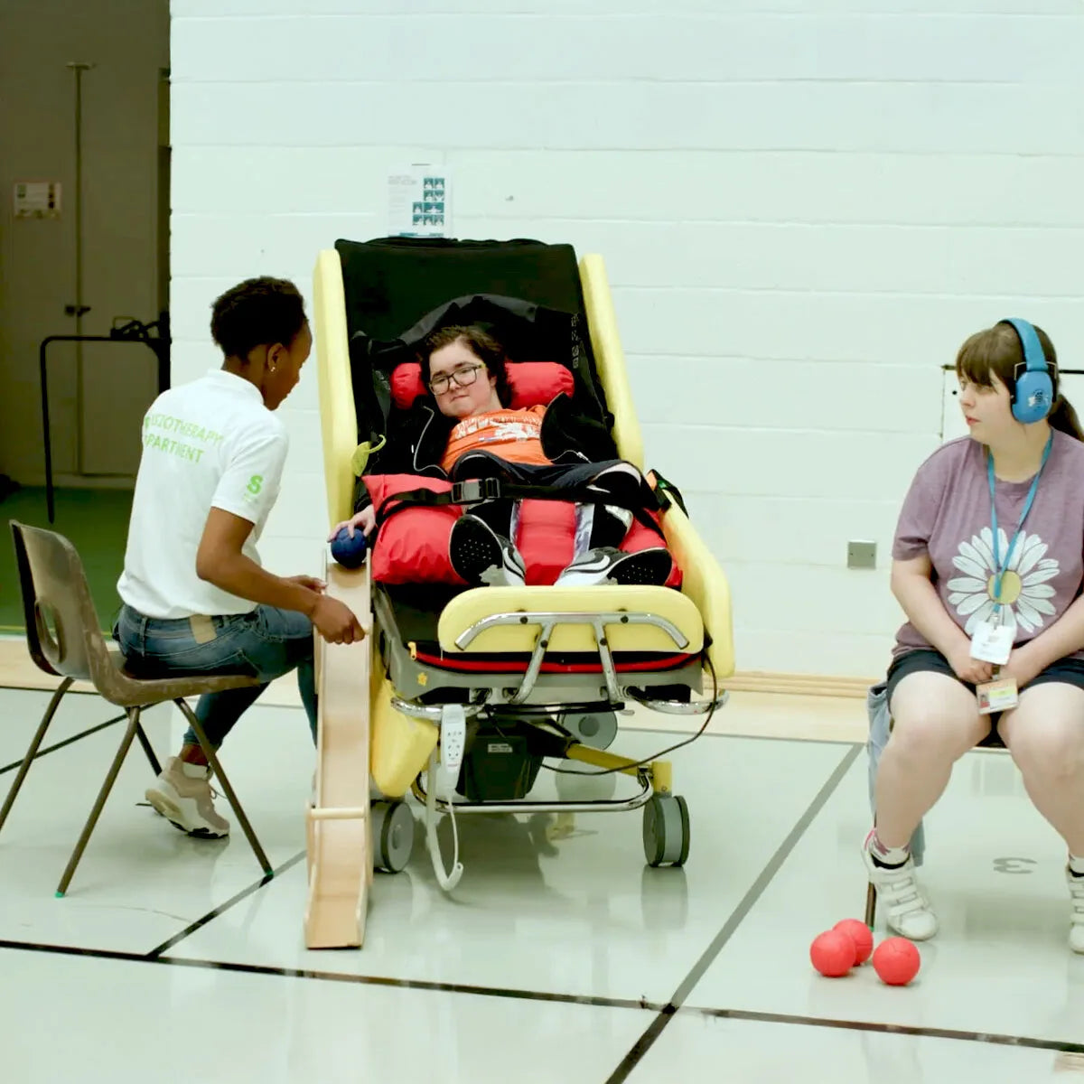 Person using an acheeva 3 with a child sitting on a chair, and another person standing nearby.