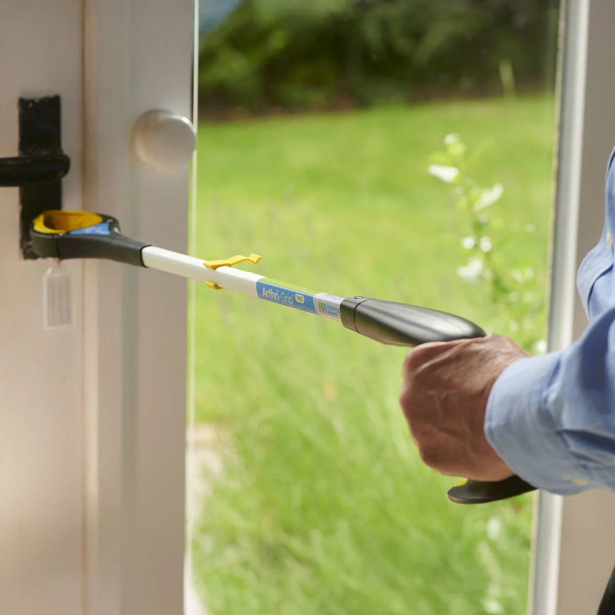 Person using a tool to open a glass door with a green outdoor background