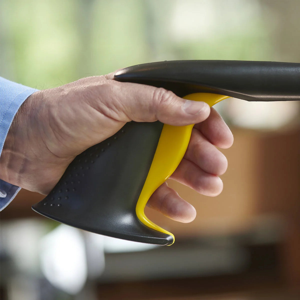 Hand holding a black and yellow tool against a blurred background