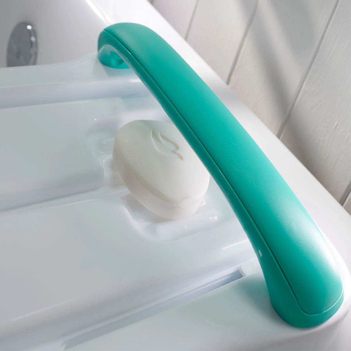 Teal handle on a white bathtub with a white soap bar.