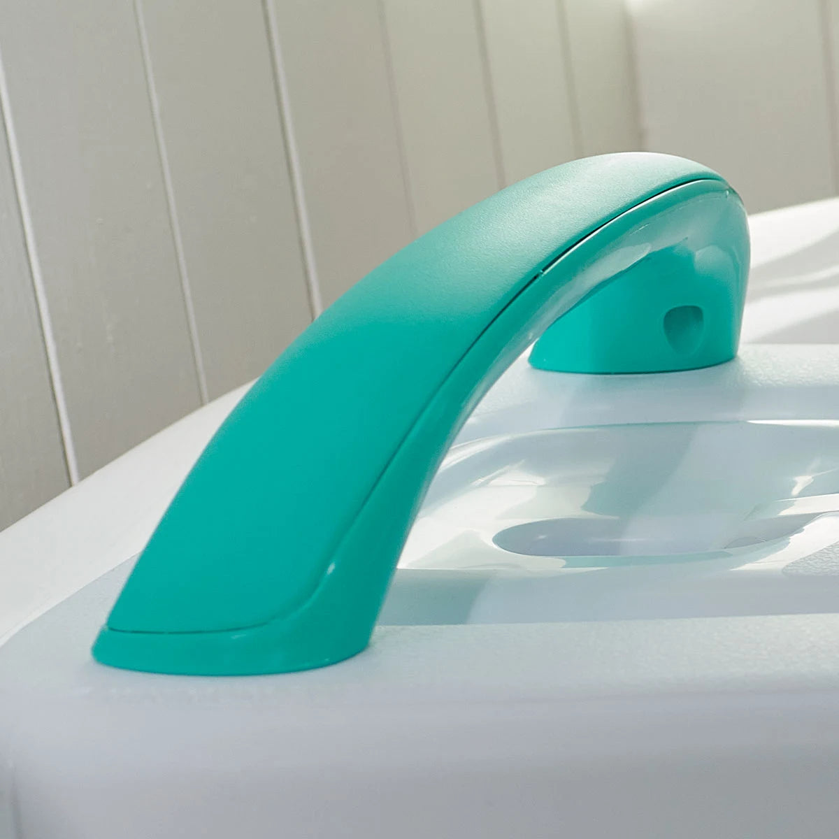 Turquoise bath handle on a white bath with a white wall background