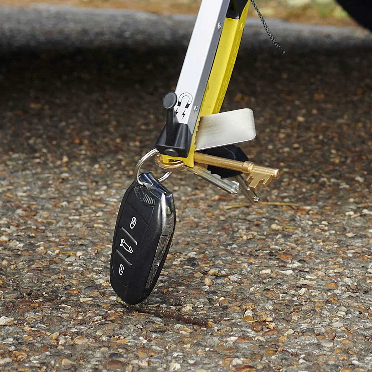 someone is picking up car keys of the floor with a pro folder reacher