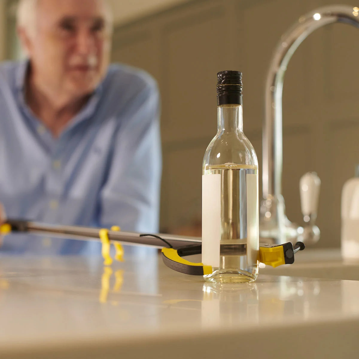 A man is using a pair of tongs to get a glass bottle