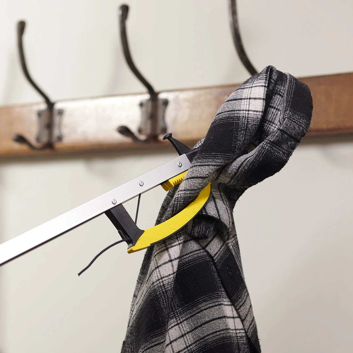 Hanging clothes with a metal rod and hooks on a white wall.
