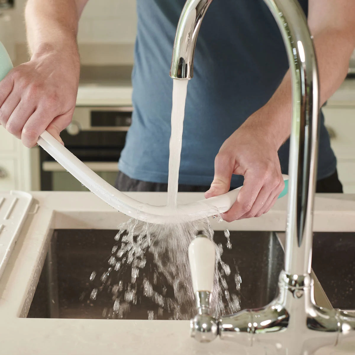 Person using a kitchen faucet to clean a bathroom sponge.