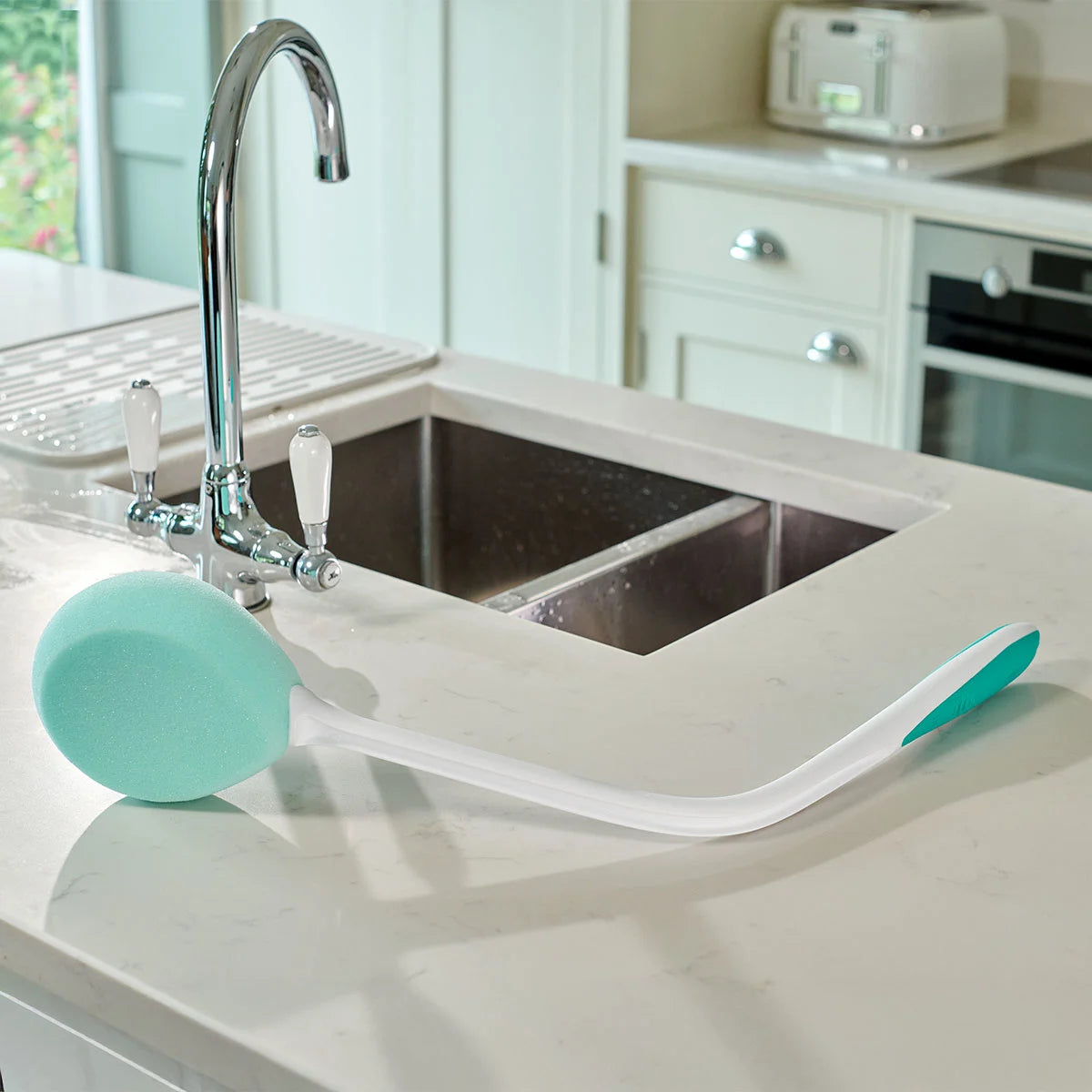A teal bath sponge next to a kitchen sink