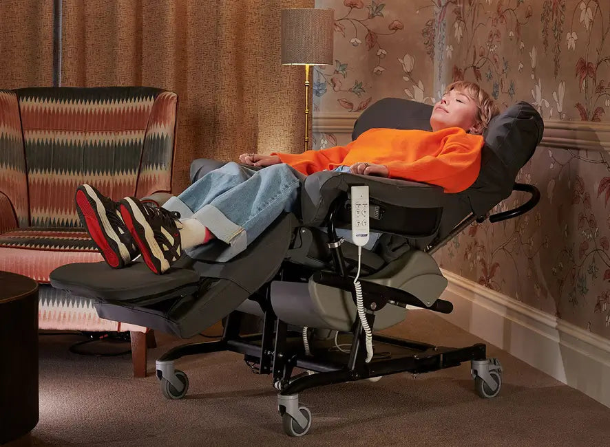 A woman reclined using the tilt-in-space function of a SymmetriSeat 70, in a living room setting.