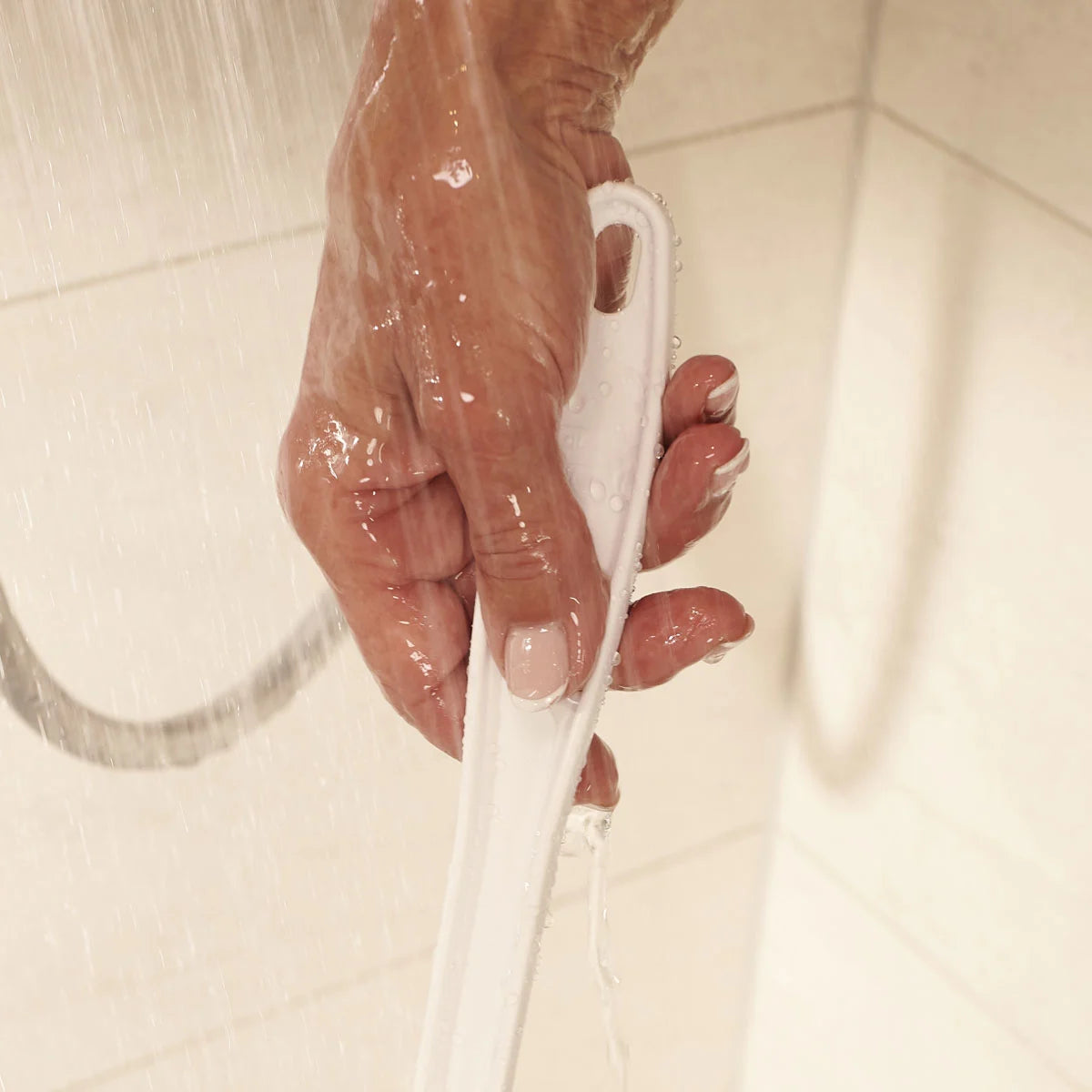 Hand holding a white shower bath sponge under running water
