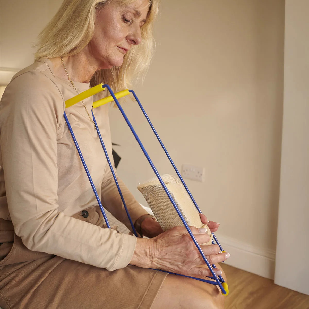 A woman putting a stocking on a sock aid