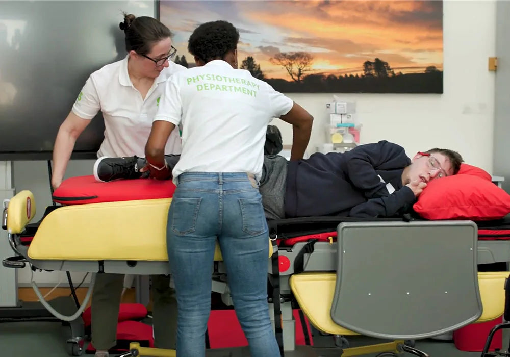 Two healthcare professionals attending to a patient on an acheeva in a clinical setting.