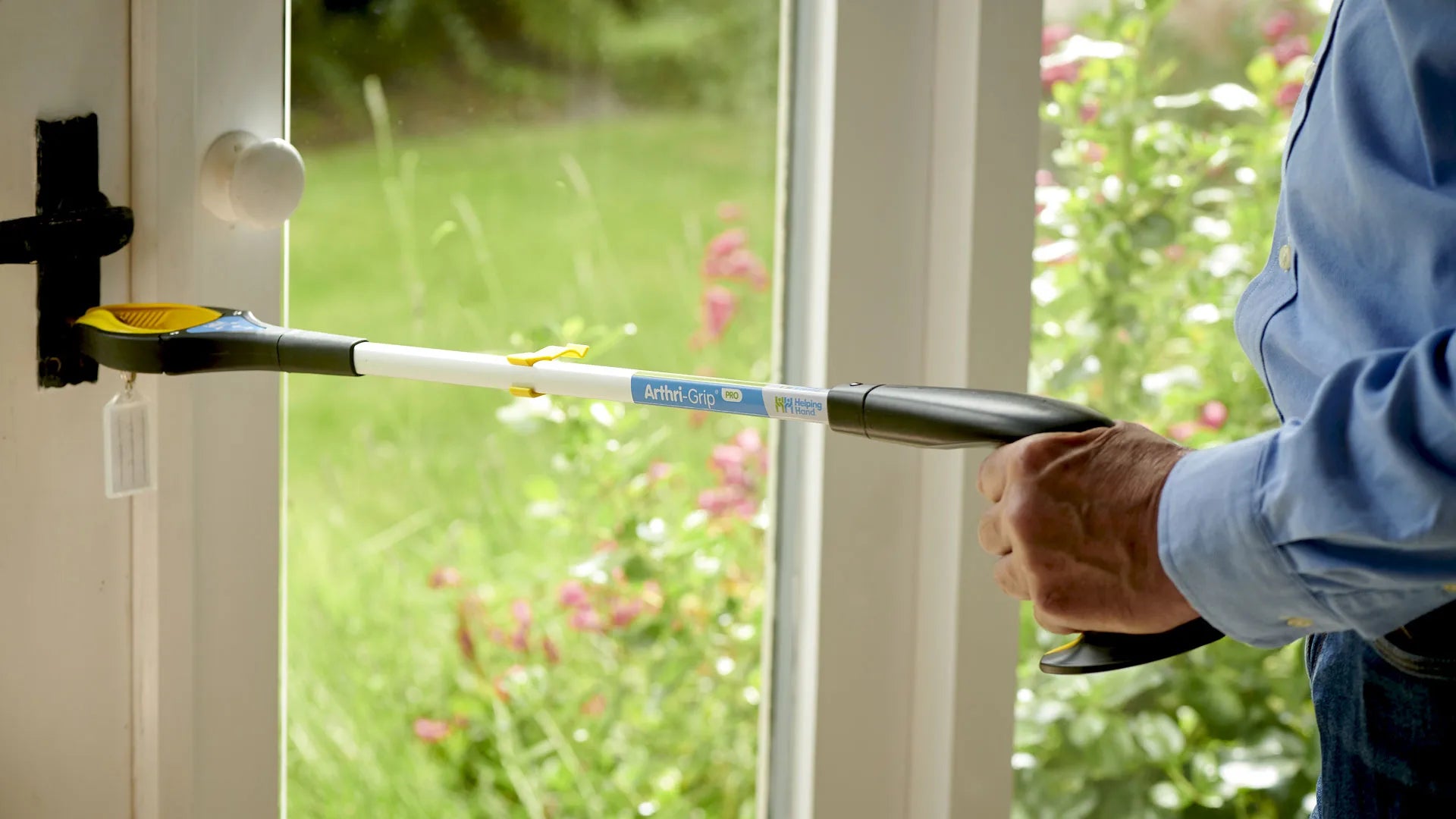 A person using a tool to get keys out of a glass door