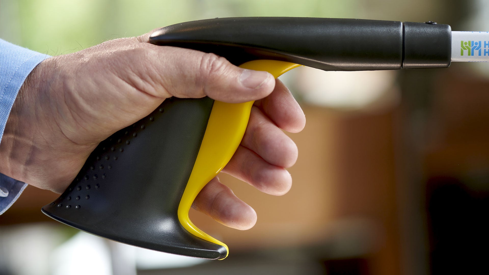 Hand holding a black and yellow cleaning tool with a blurred background