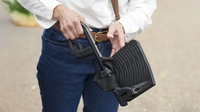 Person holding a black step stool used in wheelchairs with a blurred background