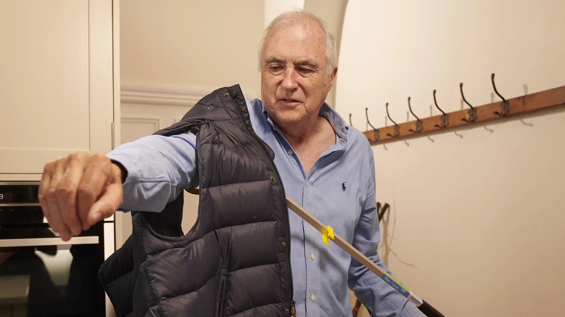A man is using a pair of tongs to put on a black vest