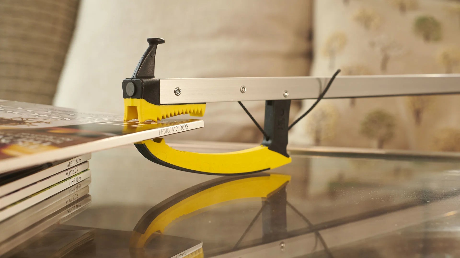 Someone is using a pair of tongs to grab a magazine off a glass table