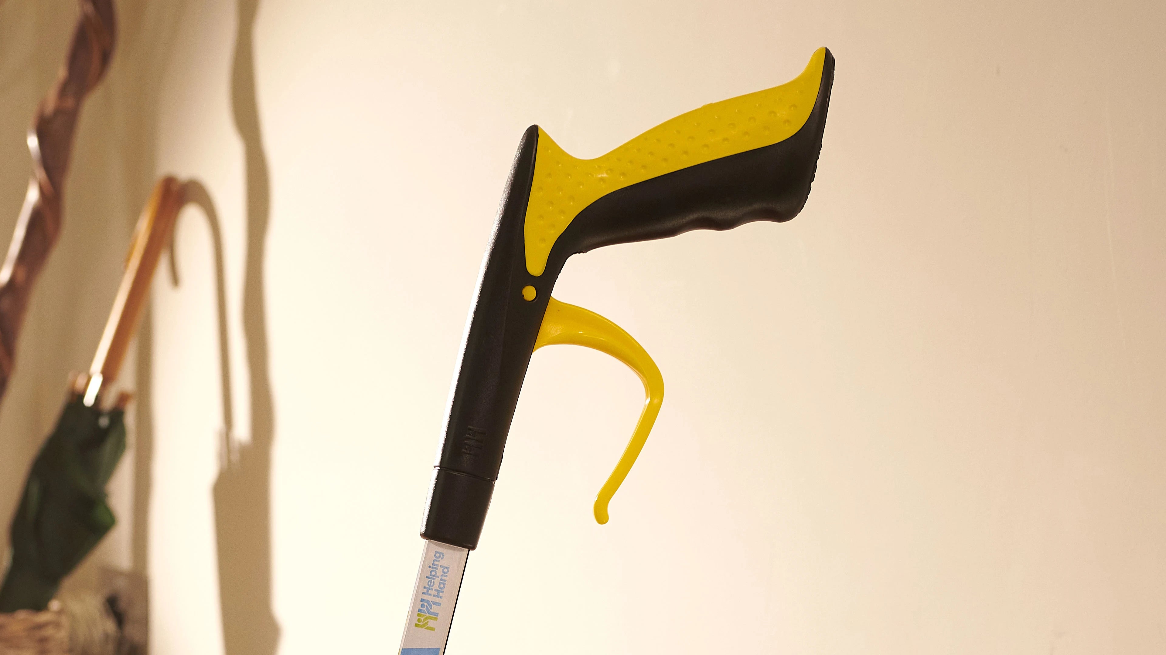 Tongs with yellow handle against a neutral background