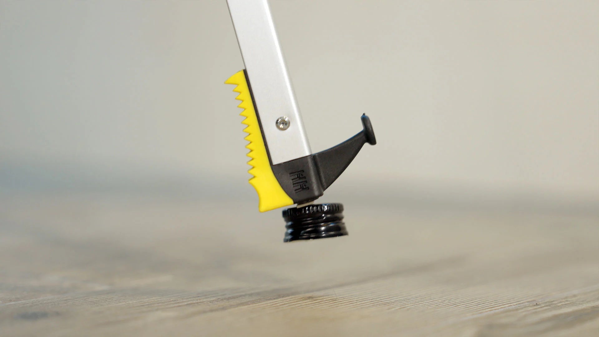 A pair of tongs with a magnetic end picking up a bottle cap