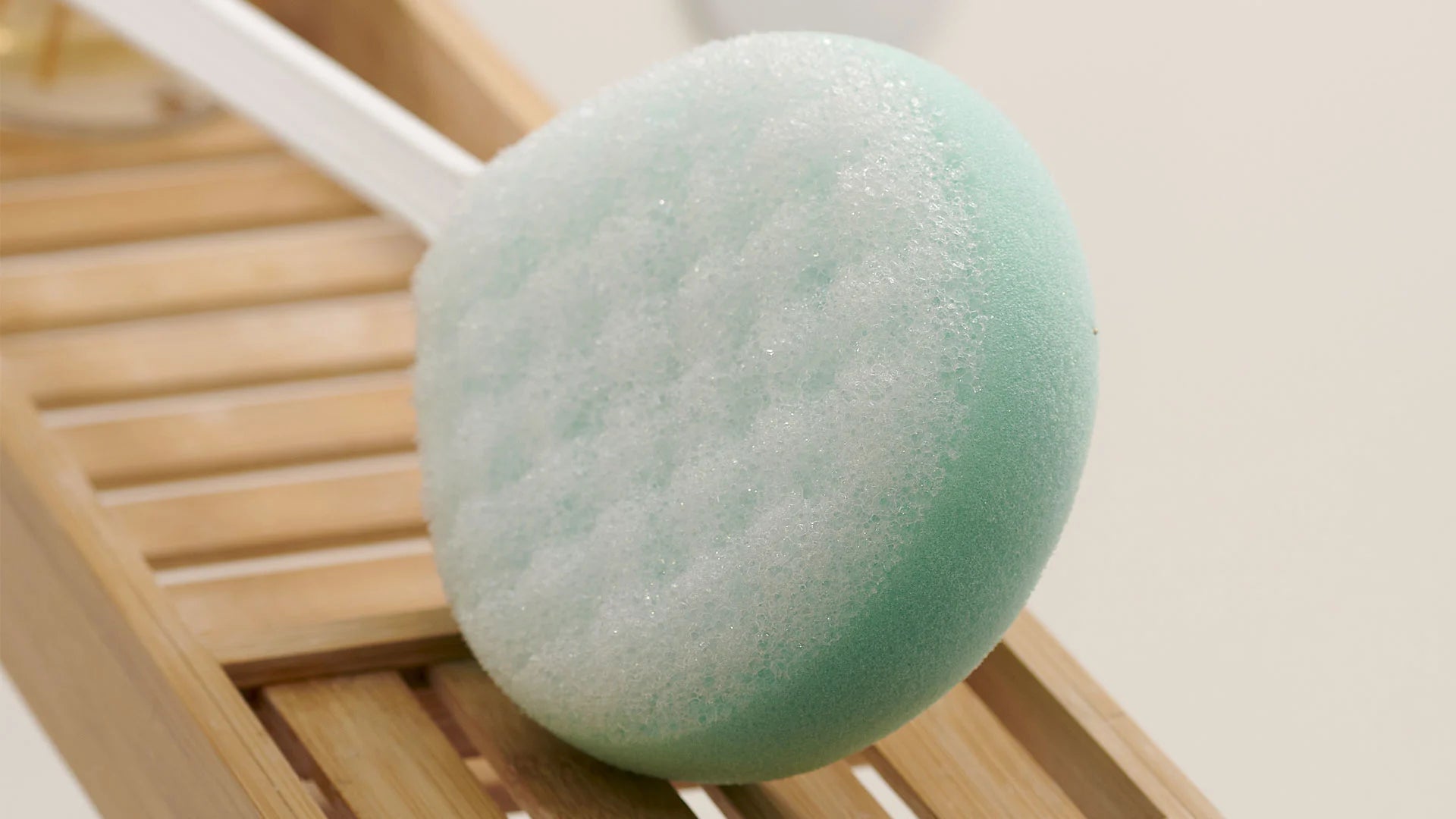 Green bath sponge on a wooden surface with a white background