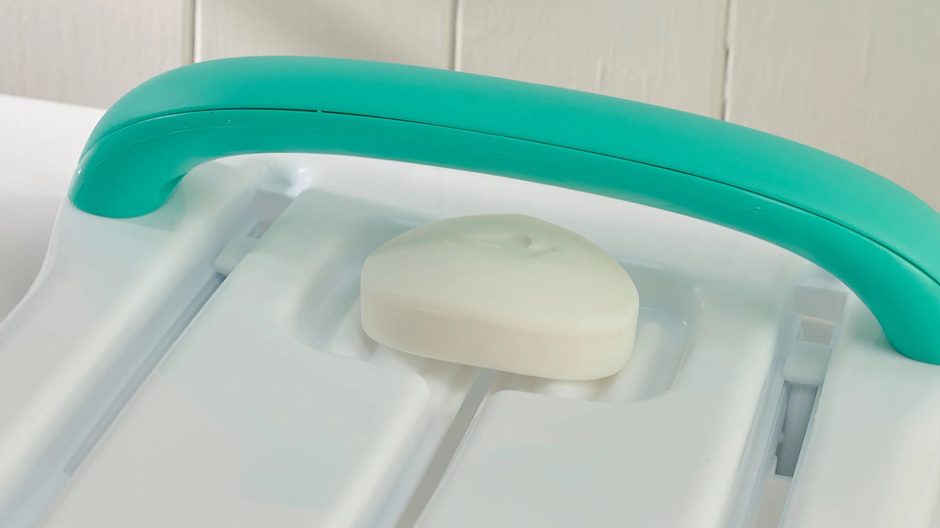 A turquoise handle with a white bar of soap on a white background