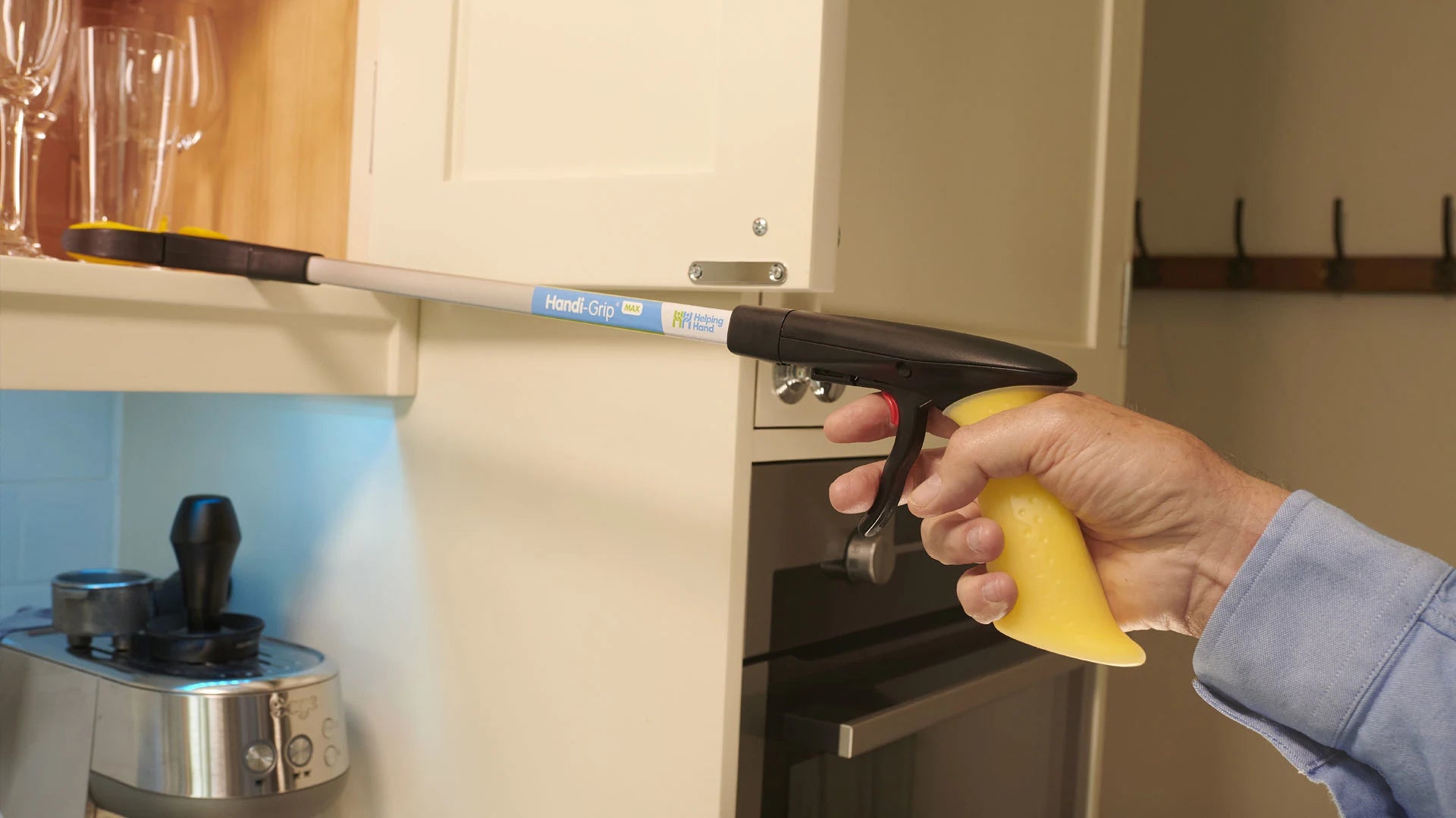 A person using a maxi grip to grab a glass from a cupboard