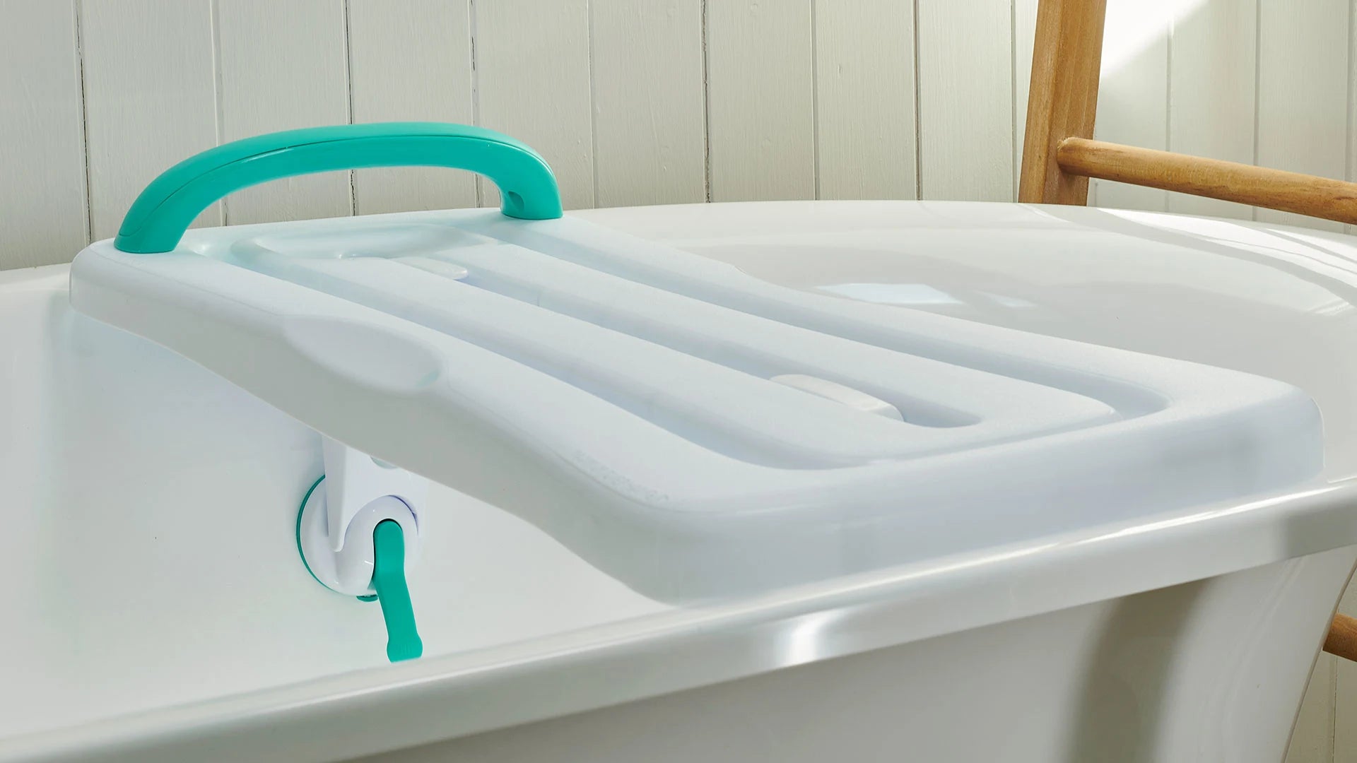 Bathtub with green handle and white board against a white tiled wall.
