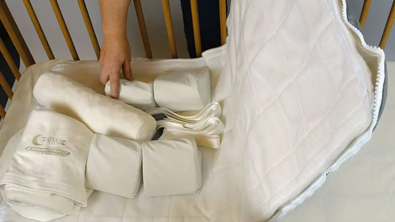Crib mattress with rolled-up mattress topper on a crib