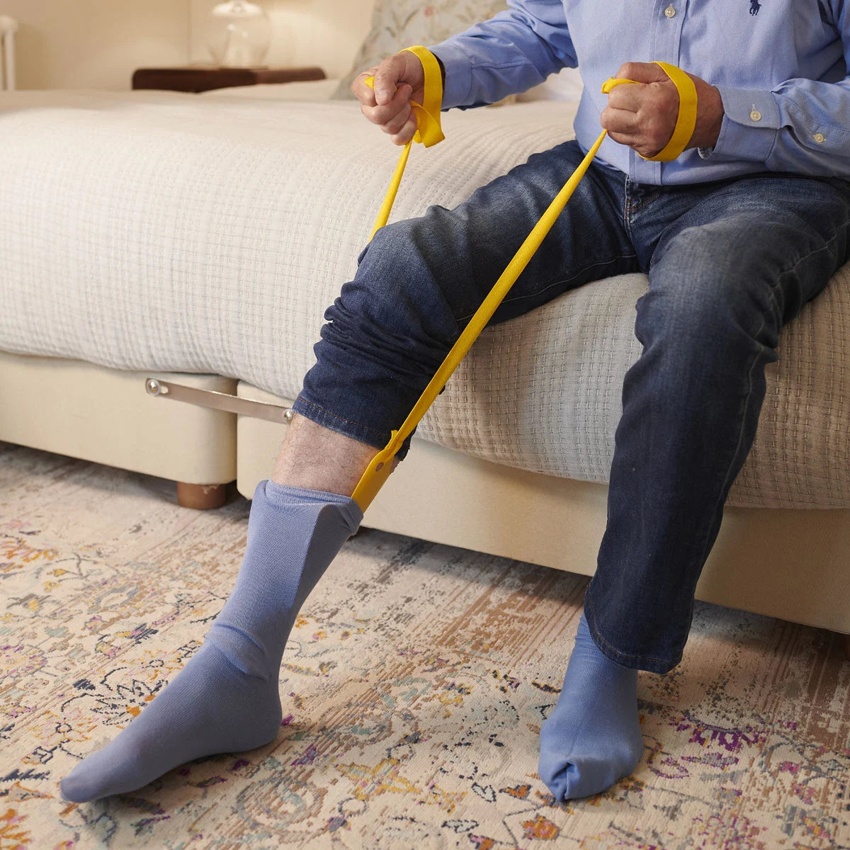 A person using a yellow sock aid to put on socks