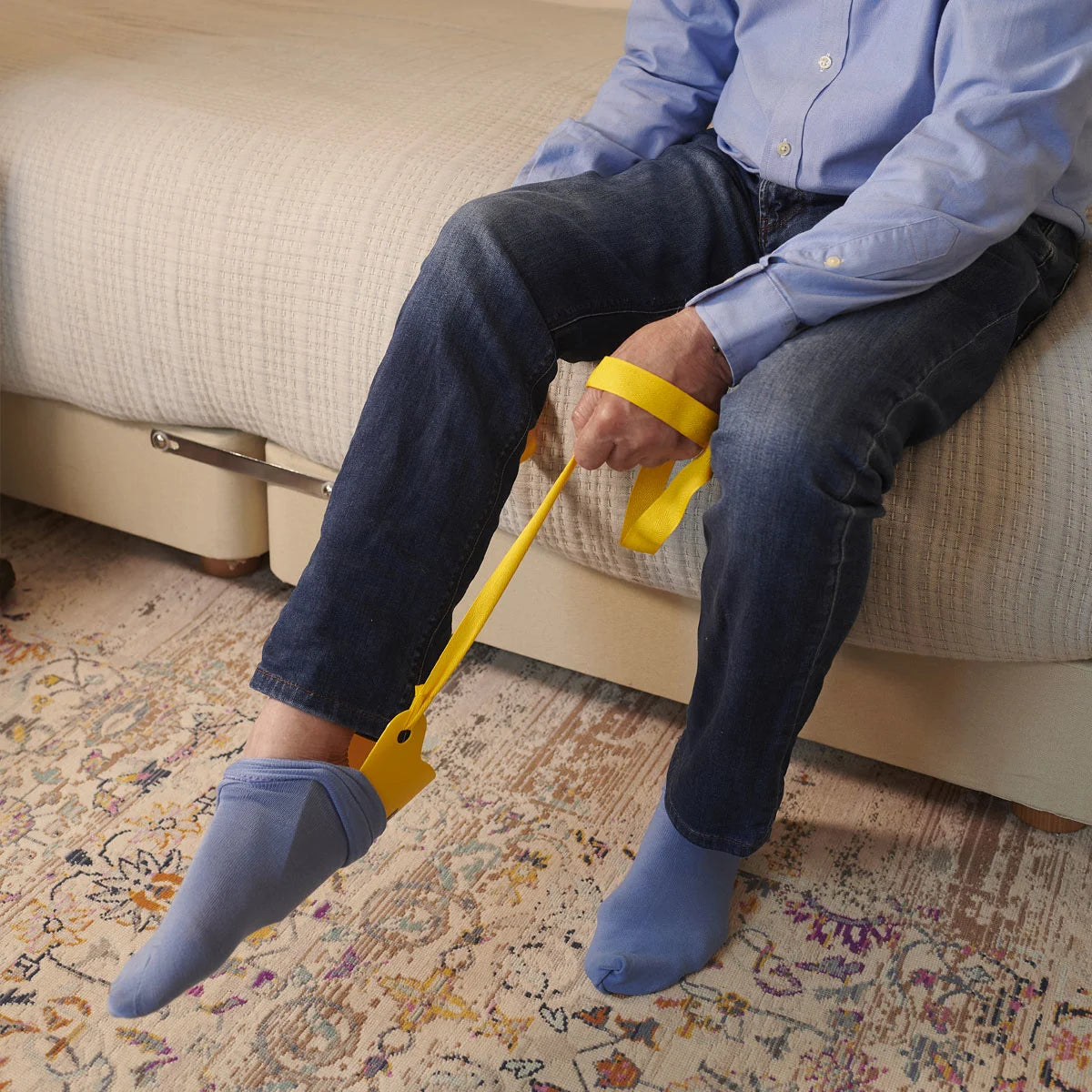 A person using a yellow sock aid to put on socks
