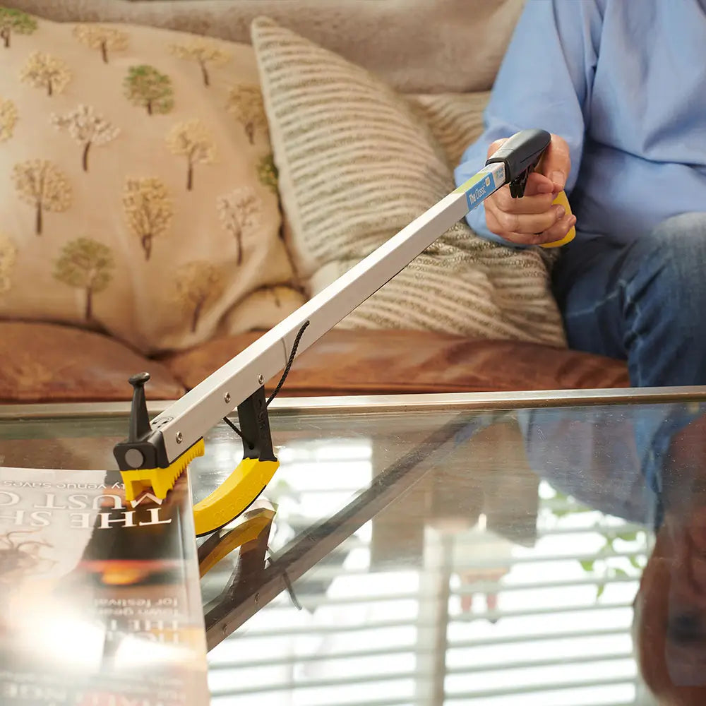 Person using a Classic PRO Reacher Grabber to pick up a book off a table.