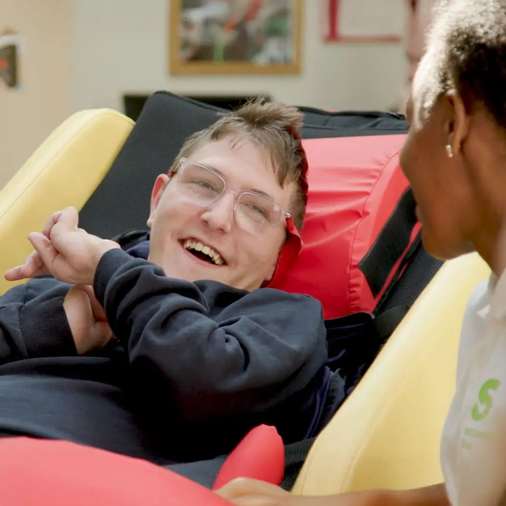 Person lying on a Acheeva Learning Station, smiling at a carer.