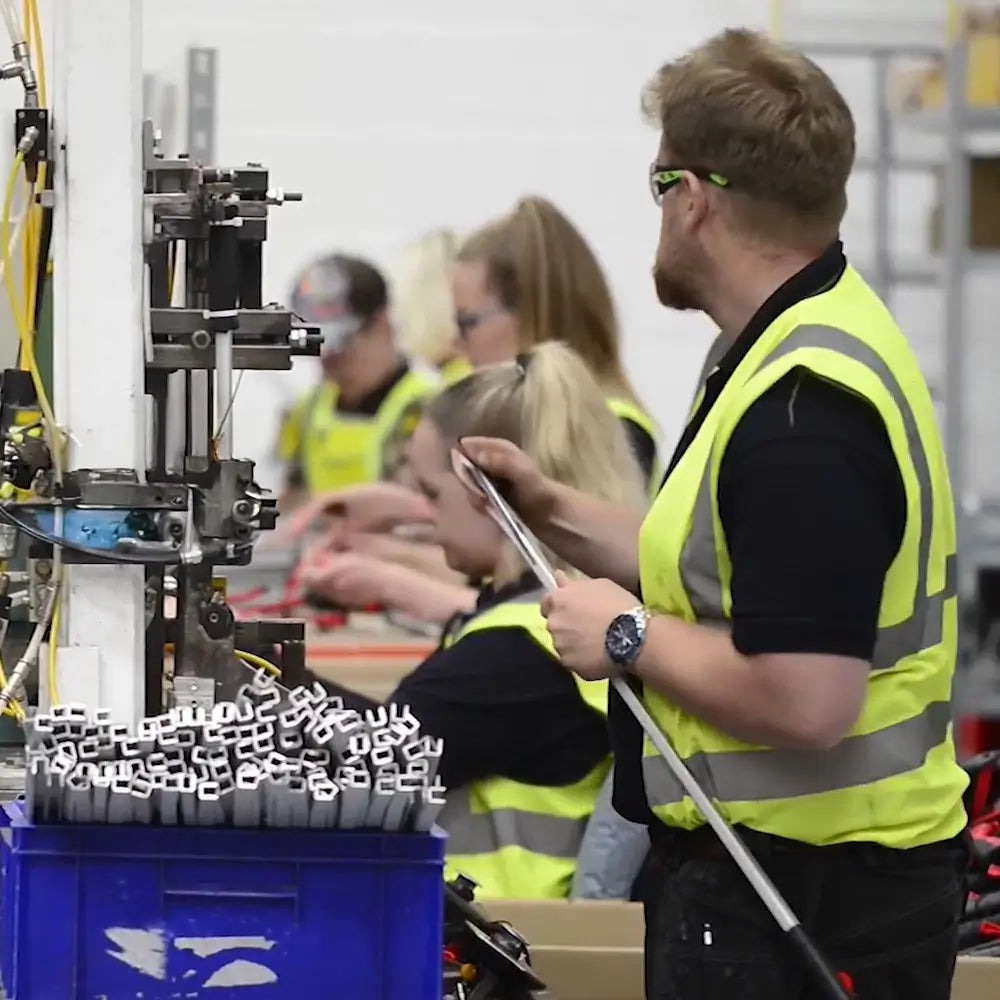 Helping Hand employees in a factory setting with machinery and safety vests.