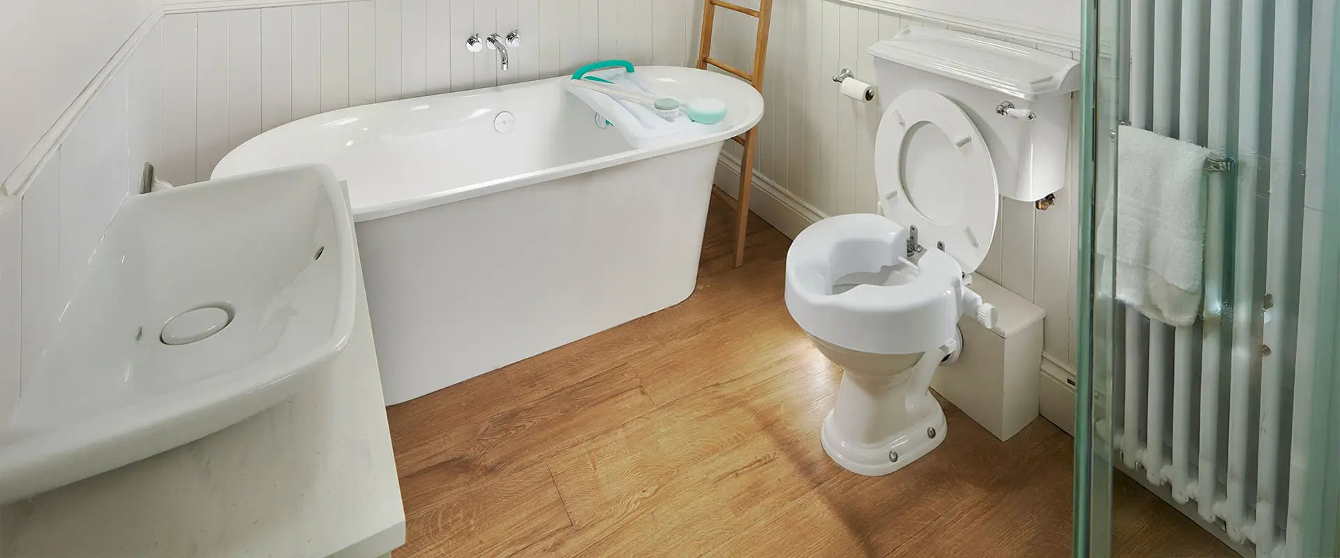 Bathroom with a bathtub, sink, and toilet with a raised seat and walker.