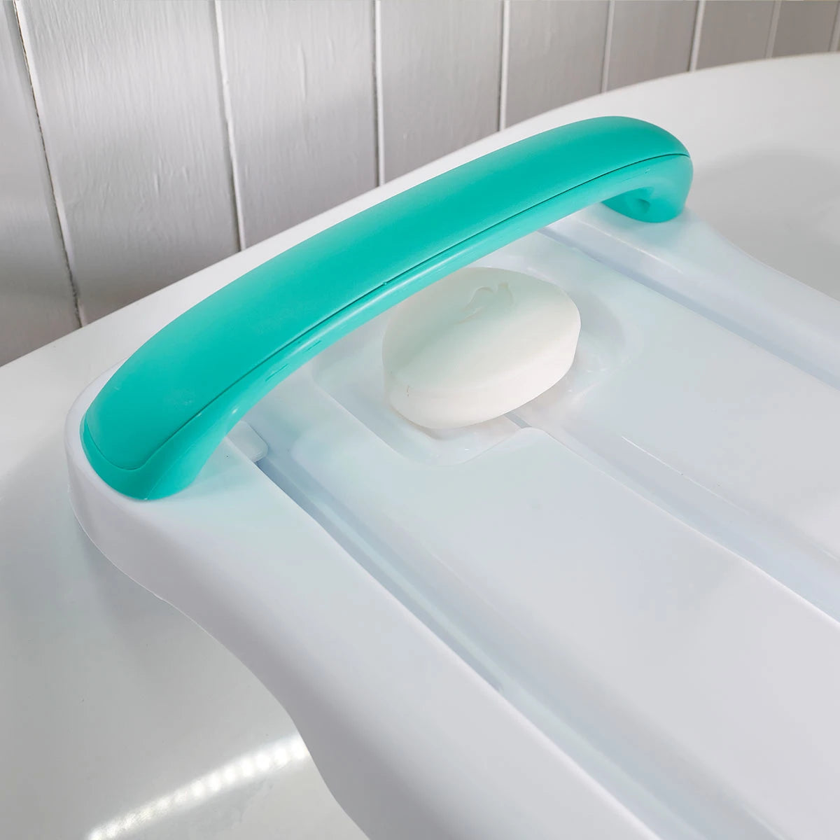 White board with a turquoise handle against a white tiled wall.