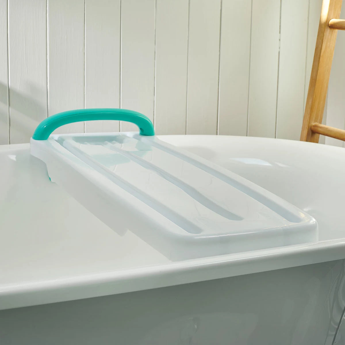 A white bath tray with a turquoise handle