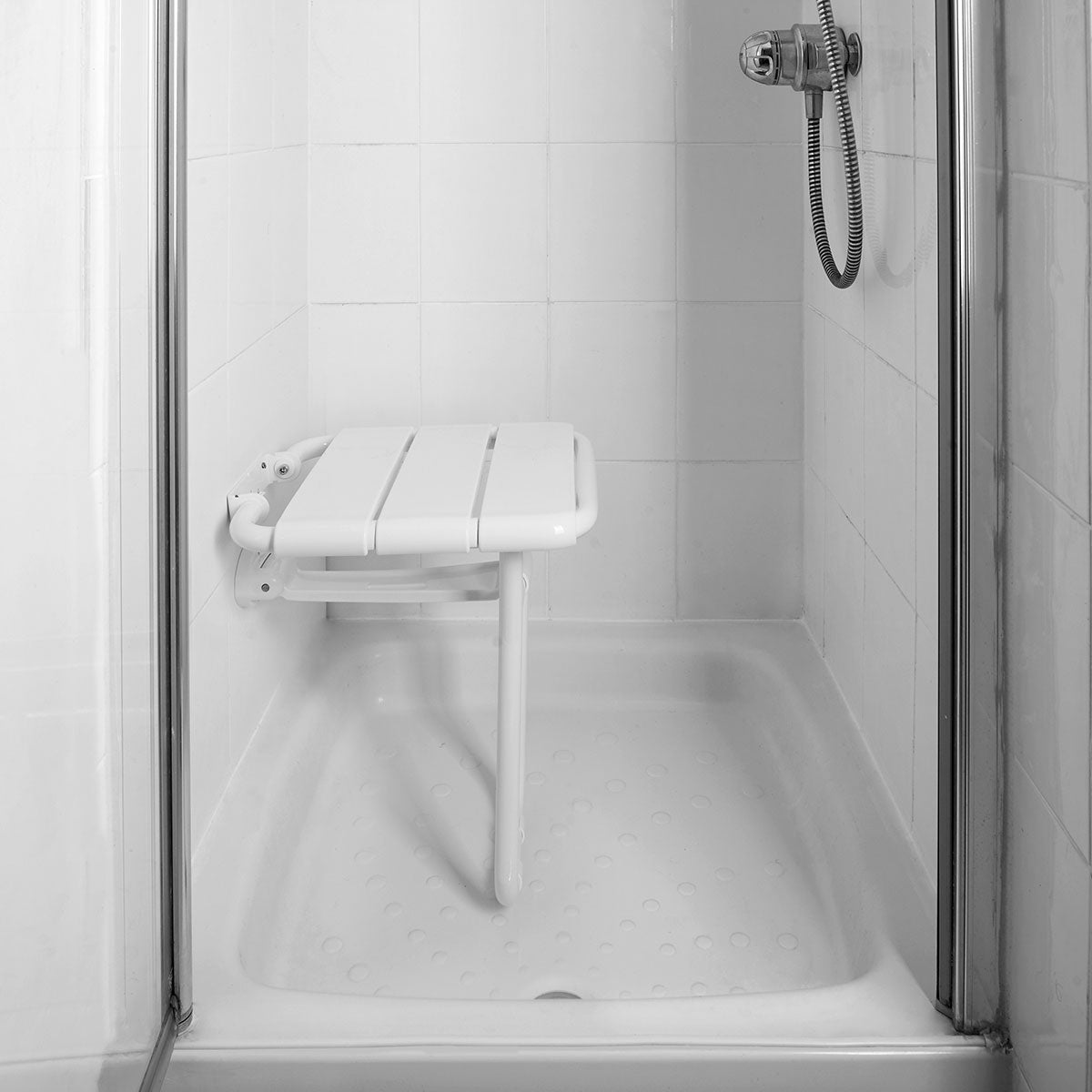 Foldable shower seat in a tiled shower enclosure