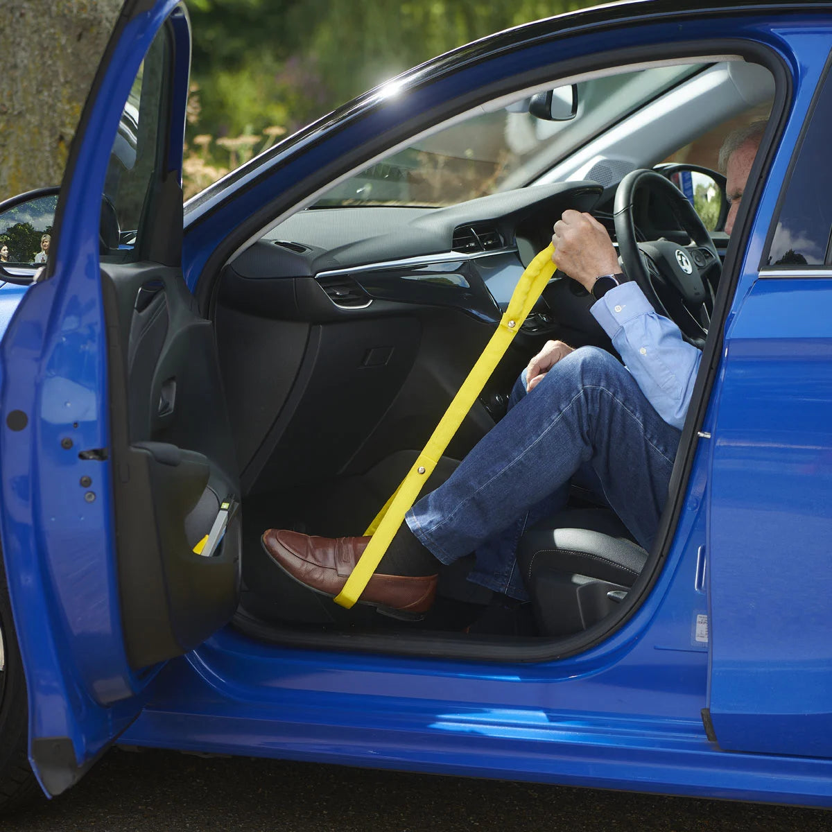 A person using a leg lifter to get out of a car
