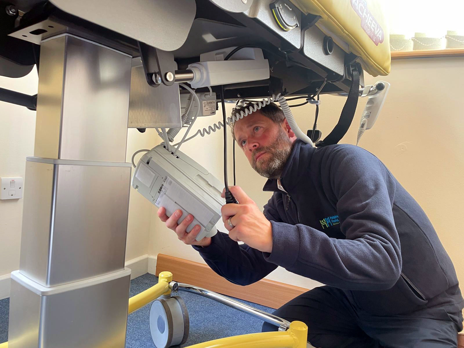 Person working on a piece of medical equipment in a clinical setting
