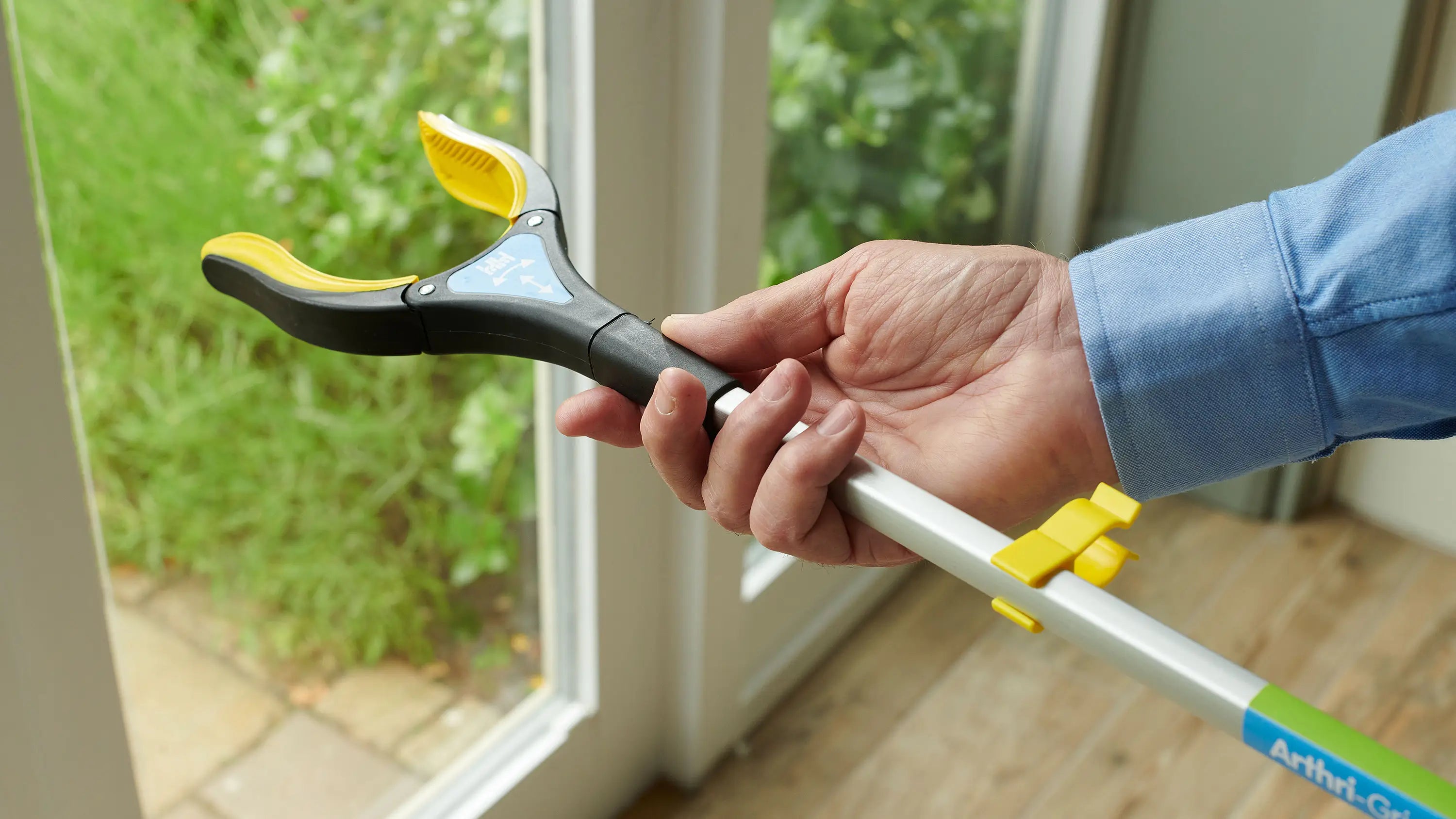 Person holding a Arthri-Grip PRO Grabber inside a house.