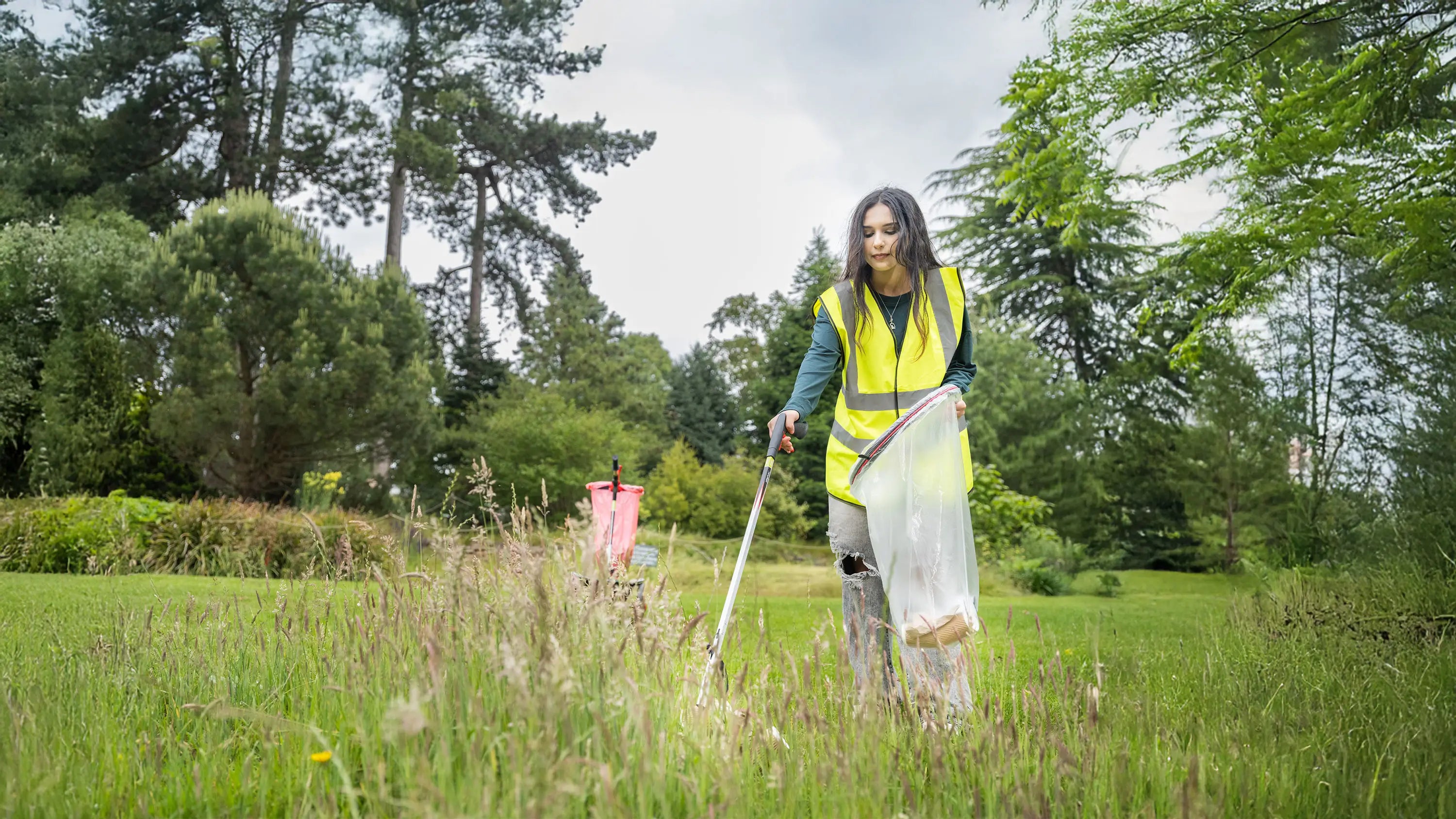 Person in a park using a Helping Hand litter picker to collect rubbish.
