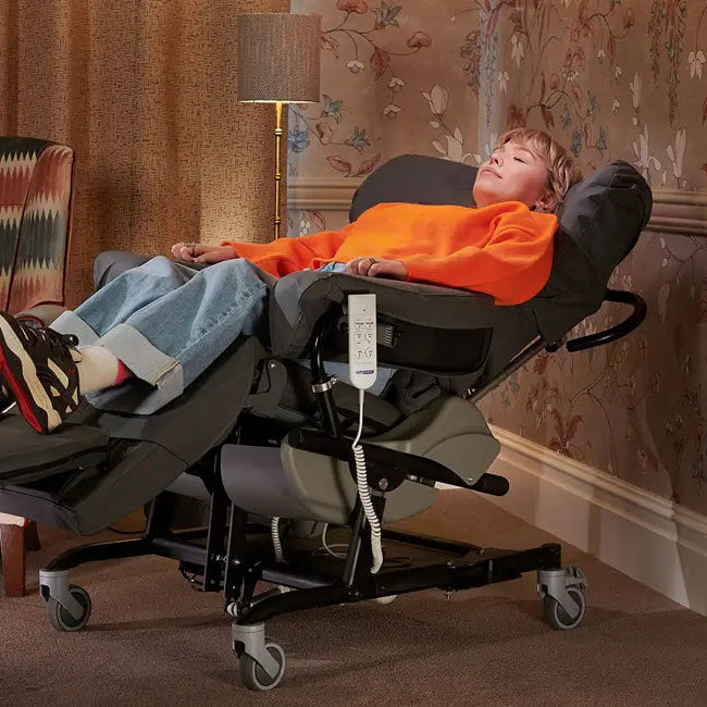 A woman reclined using the tilt-in-space function of a SymmetriSeat 70, in a living room setting.