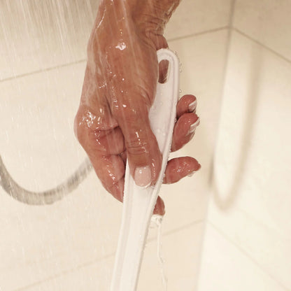 Hand holding a white shower bath sponge under running water