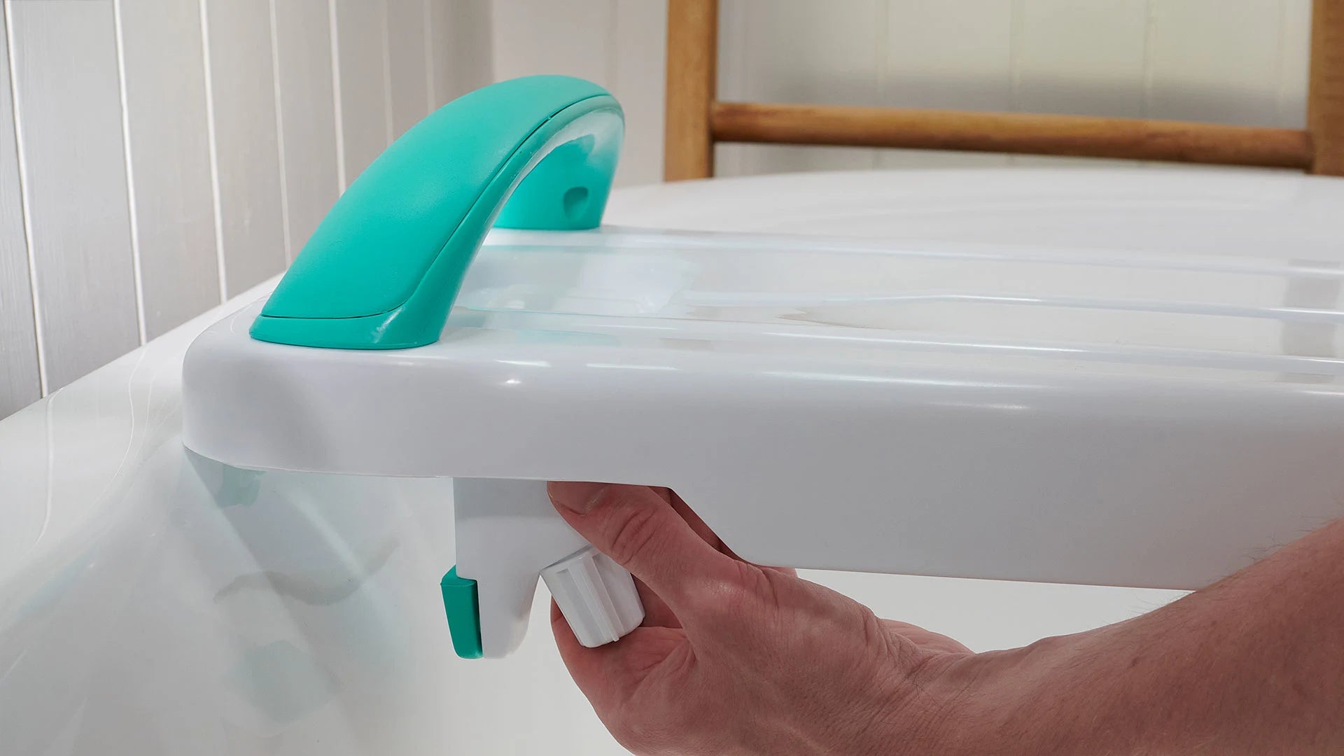 A person adjusting a bath support device with a turquoise handle
