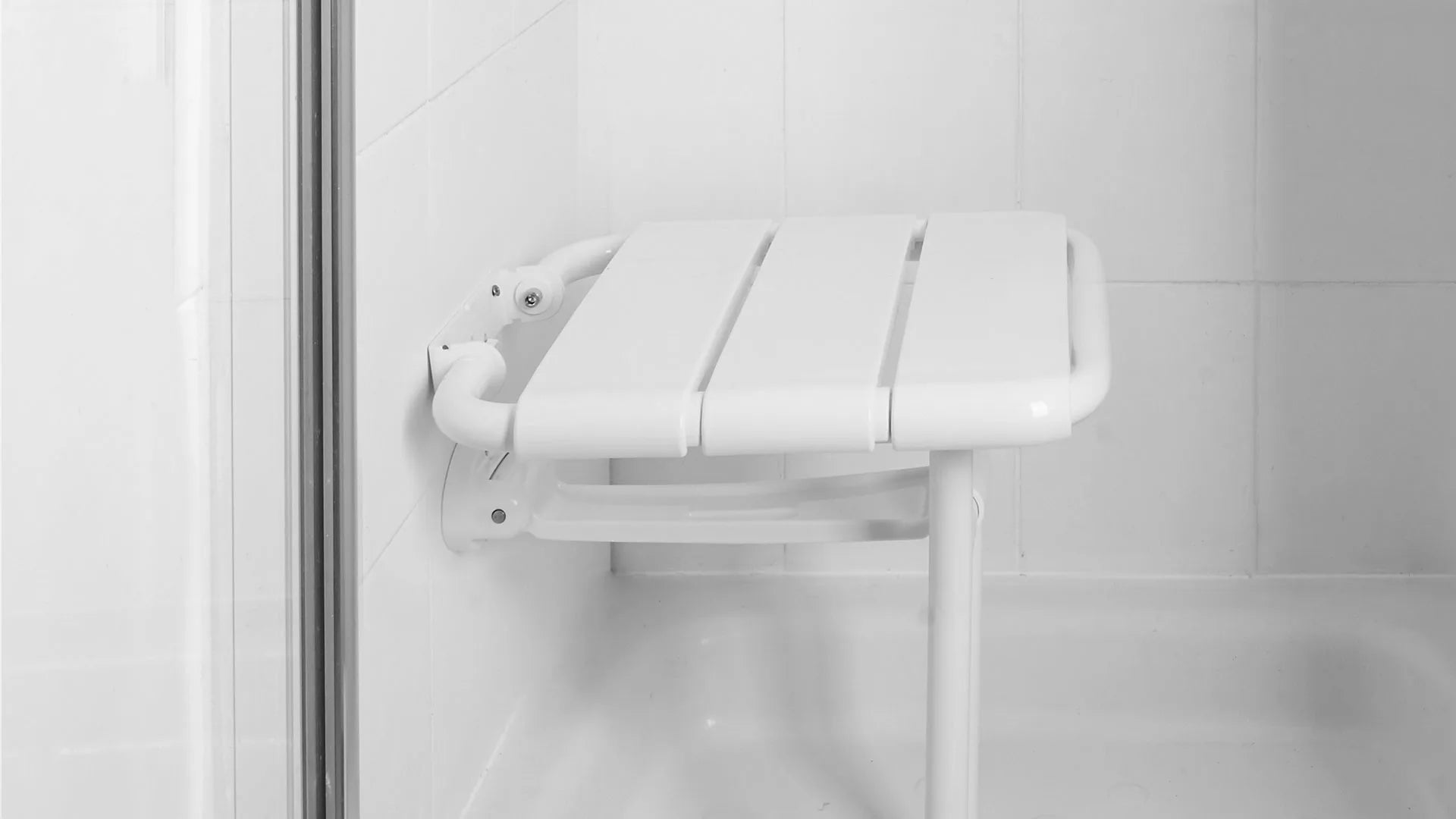 Foldable white shower seat mounted on a tiled bathroom wall.