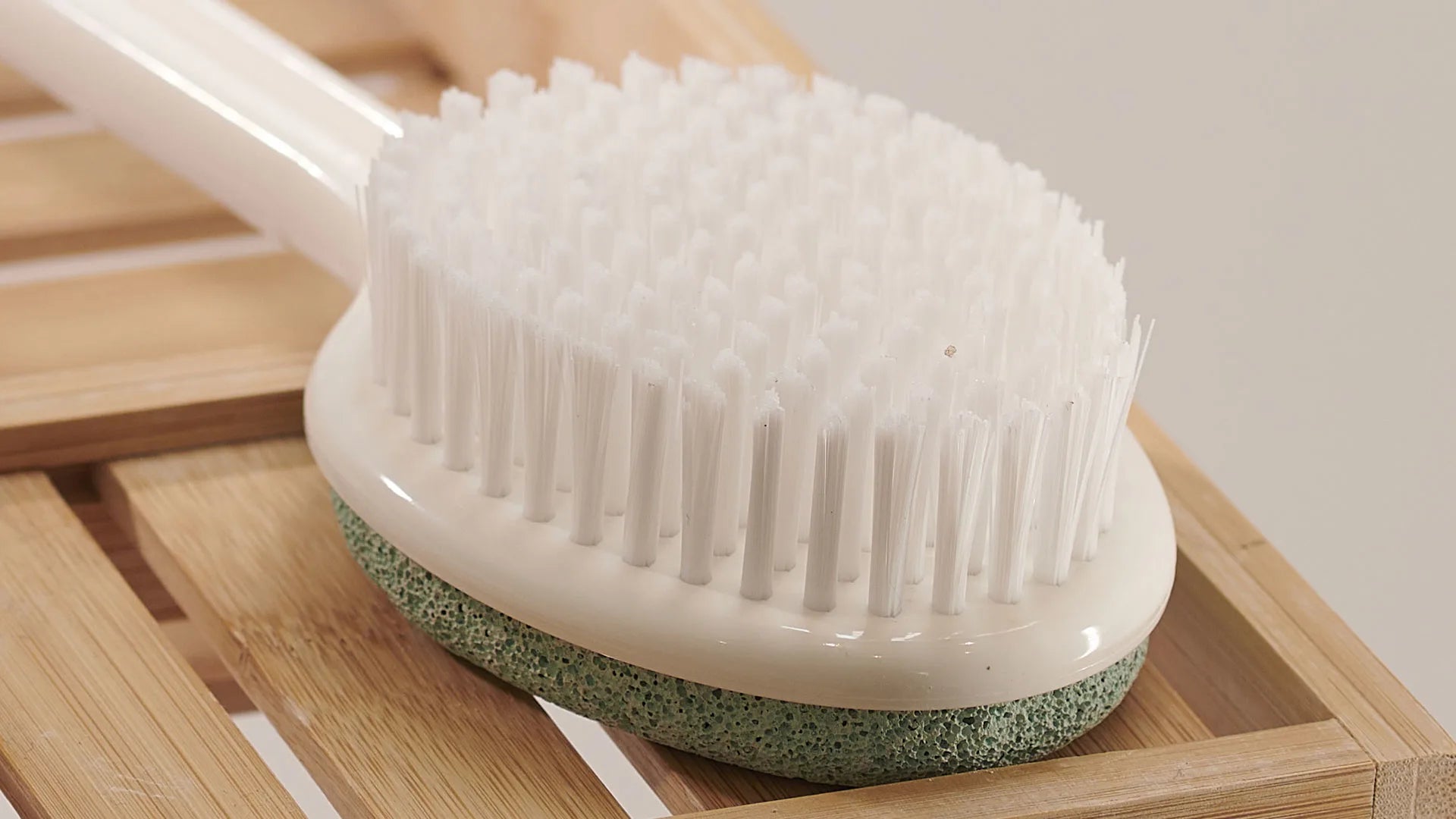 White scrubbing brush with green base on a wooden surface
