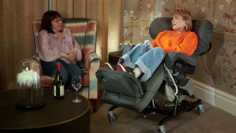 Two women in a living room setting with one in a grey reclining chair.