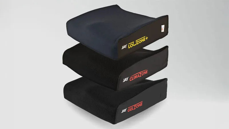 Three black cushions for a wheel chair on a grey background.