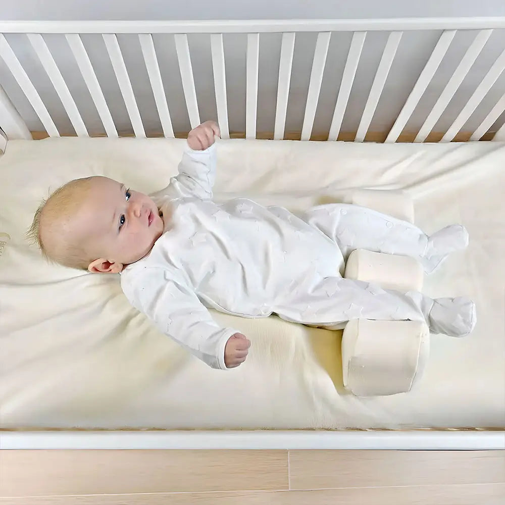 Baby lying on a SymmetriSleep Primo sleep system in a white cot.