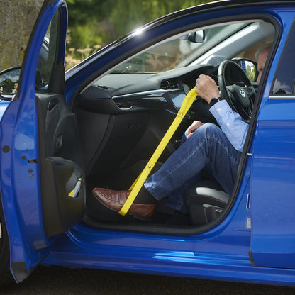 A person using a leg lifter to get out of a car
