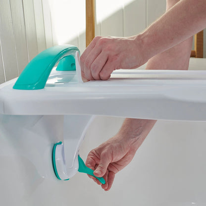 Person attaching a green bathtub support device on a white bathtub.